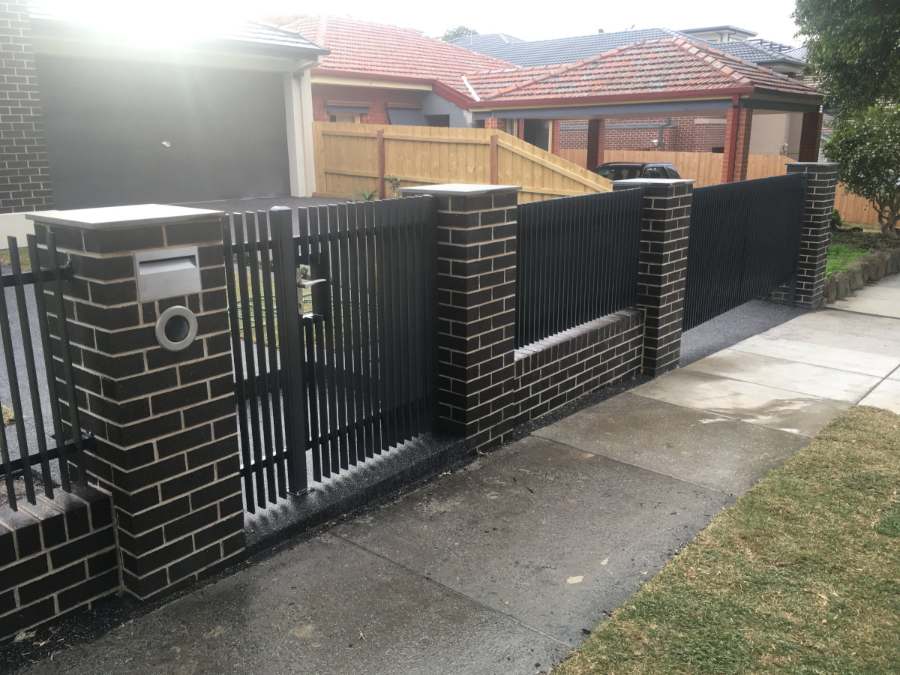 Dark brick piers with a slat gate under construction