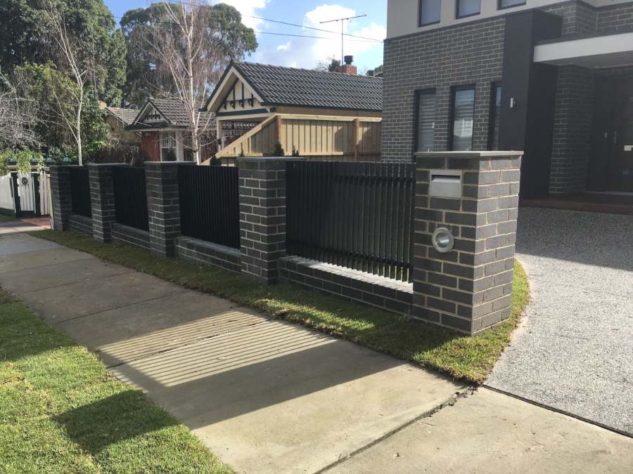 Dark brick piers with aluminium slat panels and a built-in letterbox