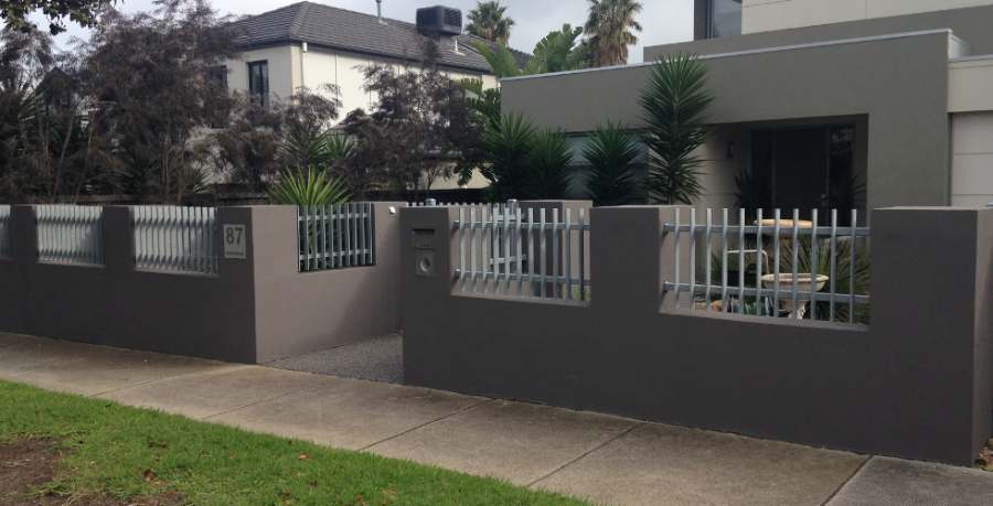 White rendered fence with slat panels in front of a modern home